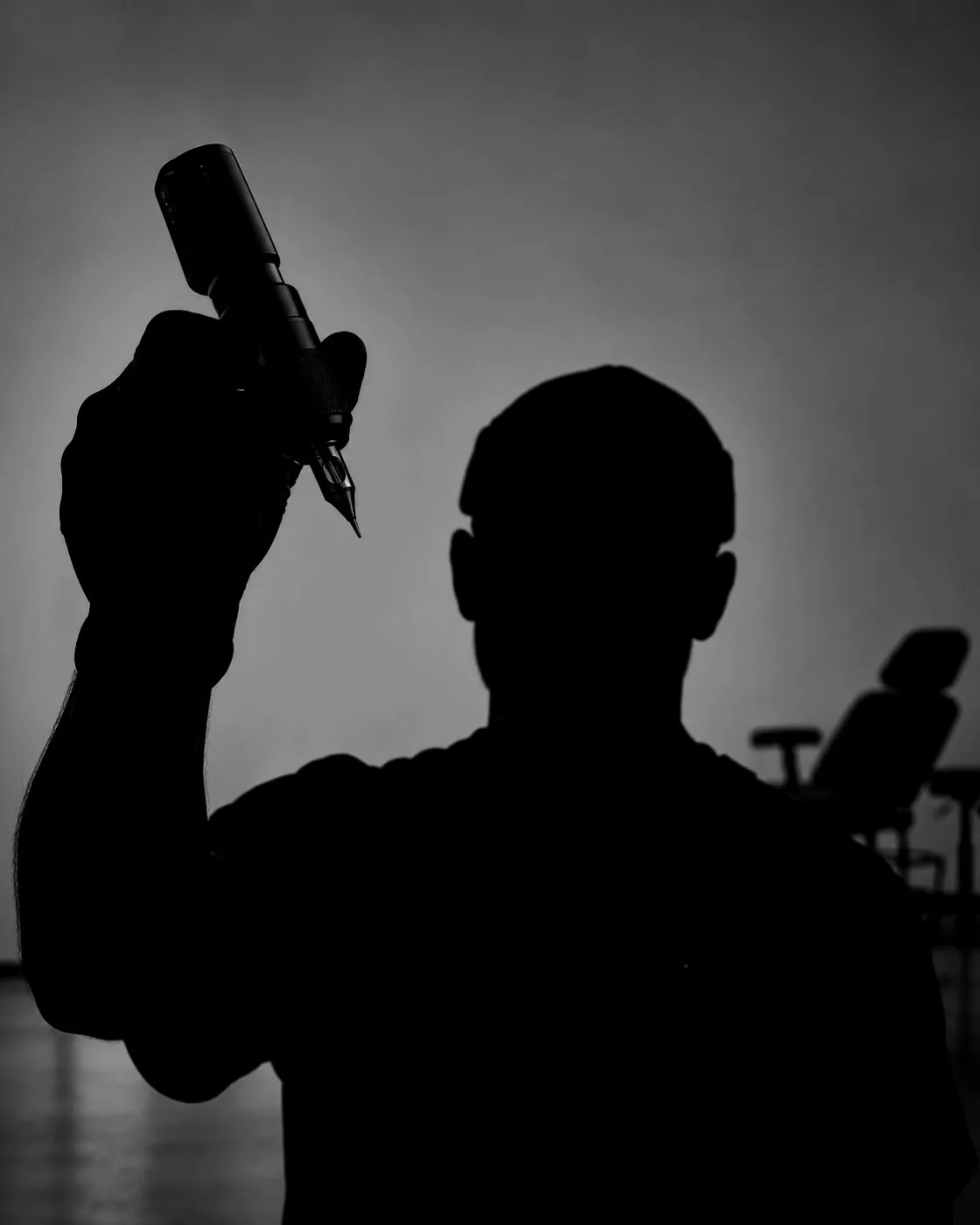 Silhouette eines Tätowierers mit Tattoo-Maschine in der Hand